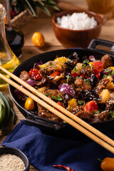 Traditional Asian sweet and sour pork with paprika and sesame. Prepared in a wok.