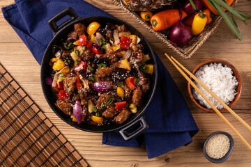 Traditional Asian sweet and sour pork with paprika and sesame. Prepared in a wok.