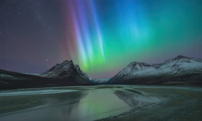 Vibrant aurora borealis glows over snowy mountains and a reflective icy lake at night