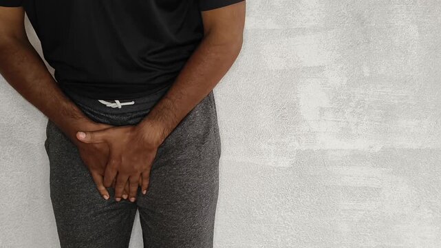 Closeup of person hand touches crotch or penis bladder isolated on white background with copy space. Uti, kidney problem, discomfort, pain, ache, urinary disease and penile cancer concept.