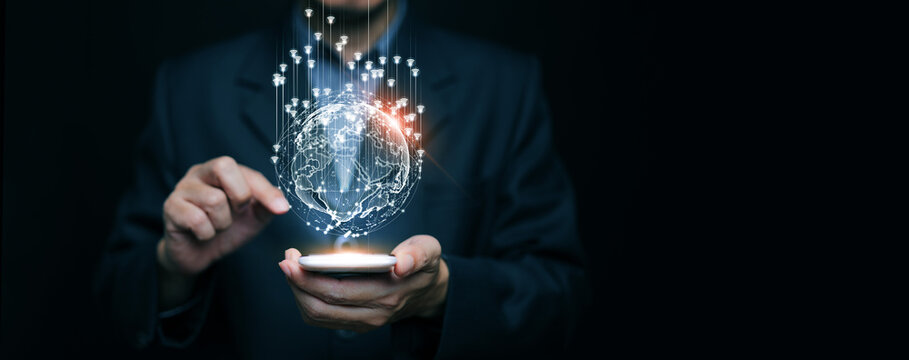 Businessman using smartphone with hologram digital globe and wireless internet icons. Global communication, smart technology, IoT, cloud computing, digital business innovation.