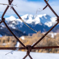 Mountains viewed through chain-link fence