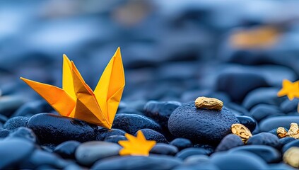 Yellow origami swan and golden nuggets on dark stone beach