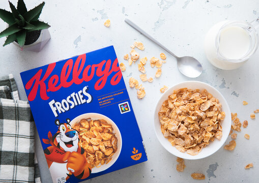 LONDON,UK - MAY 28, 2025: Kellogg's frosties breakfast corn flakes cereal cereal in bowl plate with spoon and milk jar on kitchen table.Top view.