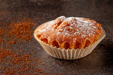 delicious cupcake in a paper baking form against a black background