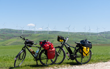 Bicycles wait on a grassy hill with wind turbines