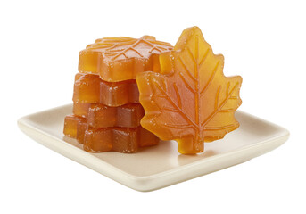 Isolated maple leaf candy, sugar cubes on a square dish, amber-colored maple candy sweets, close-up