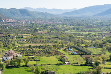 Obraz premium Rolling green hills and distant town under hazy sky