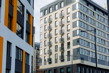 A modern residential complex with large windows and balconies. The façade features light tones with contrasting elements. Spacious balconies, panoramic windows, and a stylish design.
