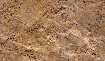 Close-up of rough brown stone surface with natural cracks and texture. Ideal for backgrounds, geology studies or construction and design concepts.