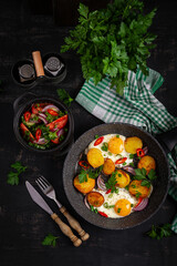 Fried eggs and potatoes with onions and chili peppers in a rustic style. Top view, flat lay