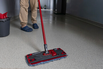 Cleaning the floor with a mop in a hallway during daytime