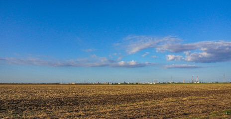 A rural field with power lines under a blue sky