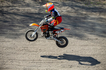 Obraz premium Child motocross rider performing jump on dusty track
