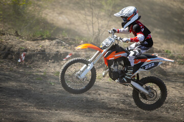 Junior motocross rider riding uphill on dusty track