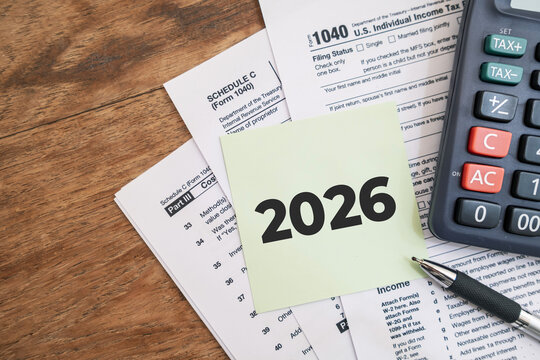 2026 numbers on the note paper with calculator and taxes documents. Marketing materials related to tax filing or fiscal year deadlines