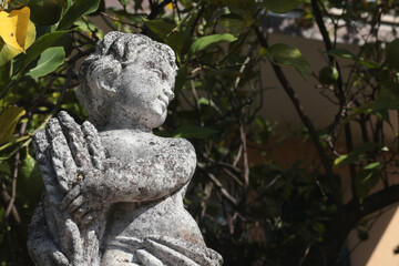 Stone sculpture near house, in park among bushes and trees. Art and design, aesthetics in Europe, Italy. Nature and seasonality. 