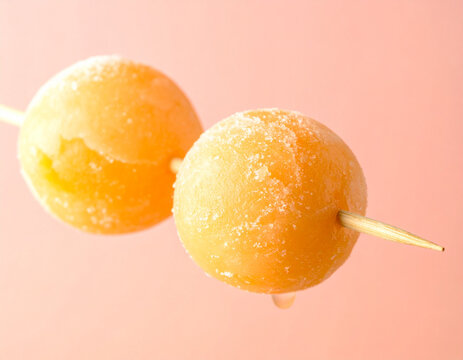 Frozen melon balls skewered, macro close-up on pastel background