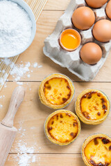 Egg tarts, eggs and other ingredients and tools on table background.