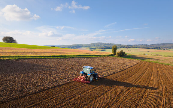 An aerial photograph of a tractor plowing a field in the picturesque countryside.