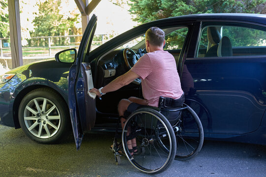 A middle-aged European man prepared to move from his wheelchair to the wheel of his car. - Powered by Adobe