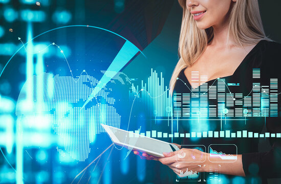 Businesswoman holding a tablet with digital data graphics, glowing charts, and world map overlay on futuristic blue background, symbolizing creative business