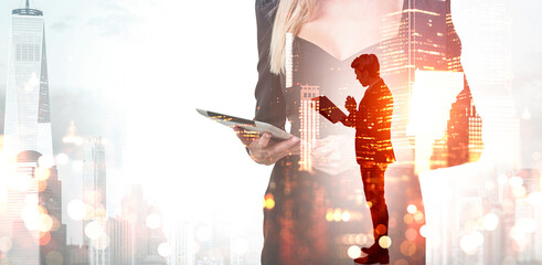 Businesswoman holding a tablet with double exposure of businessman and city buildings on a bright...