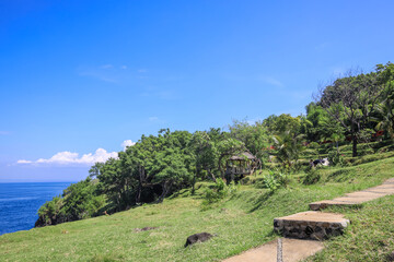 Beautiful beach with a clear blue sky and a lush green hillside