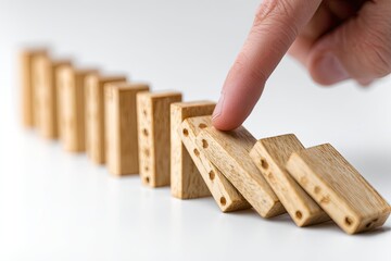 Close-up of a human finger pushing a domino, initiating a chain reaction on a white surface