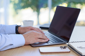 Man working on laptop at wooden table indoors, closeup