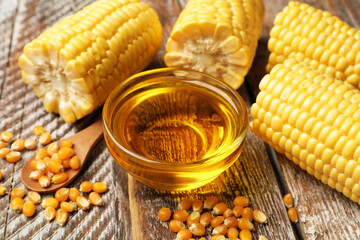Corn oil, kernels and cobs on wooden table, closeup
