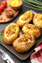 Tasty stuffed baked potatoes served on black wooden table, closeup