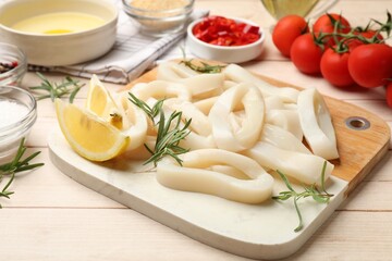 Uncooked squid rings, spices, yolk, tomatoes and bread crumbs on wooden table, closeup