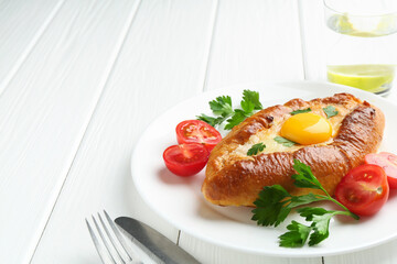 Tasty khachapuri with cheese and egg served on white wooden table, closeup. Space for text