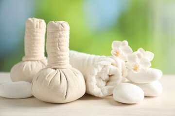 Beautiful spa composition with herbal bags on white wooden table against blurred background, closeup