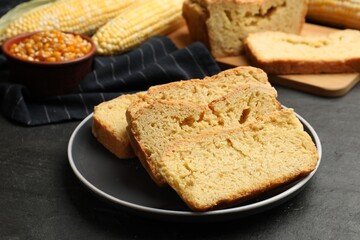 Freshly baked cornbread, cobs and seeds on black table, closeup