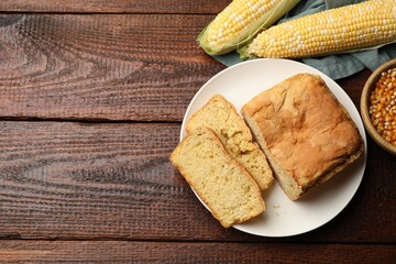 Freshly baked cornbread, cobs and seeds on wooden table, flat lay. Space for text