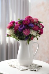 Beautiful flowers in vase on white table indoors