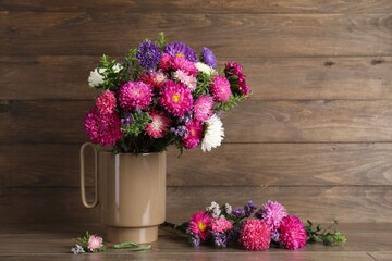 Beautiful flowers in vase on table against wooden background, space for text