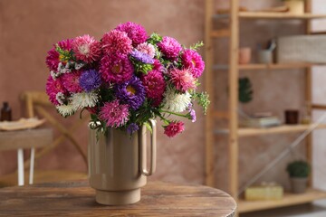 Beautiful flowers in vase on wooden table indoors. Space for text