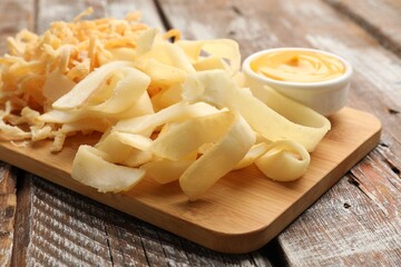 Dried shredded squid, shavings and sauce on color wooden table, closeup