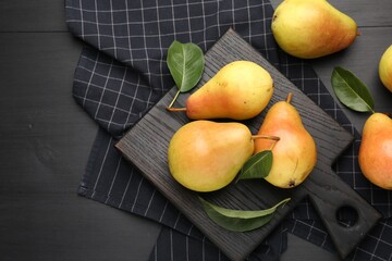 Many fresh pears and leaves on black table, flat lay