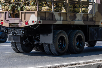 Soldiers in camouflage uniforms sitting in military truck outdoors