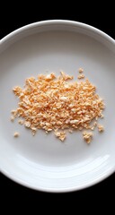 Crumbly, orange-tinged food bits are atop a plain, white plate