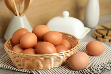 Raw chicken eggs and kitchen utensils on wooden countertop, closeup