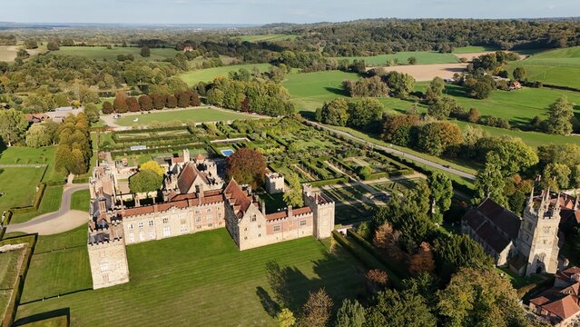 Aerial view of Penshurst Place's weathered stone walls and manicured gardens contrast with the wild, sprawling greenery beyond, Tonbridge, England, United Kingdom.