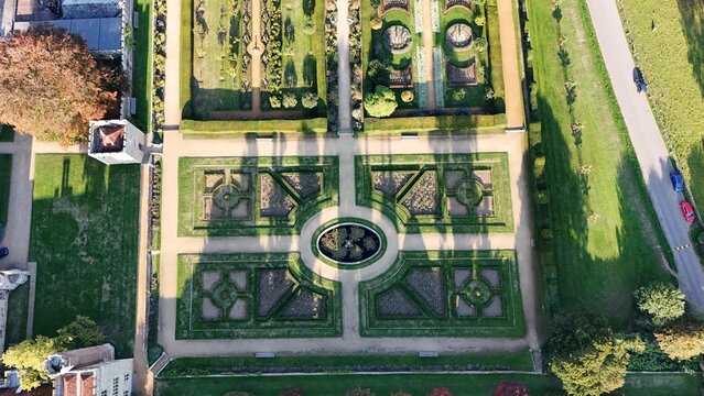 Aerial view of Penshurst Place Gardens unveils a tapestry of manicured lawns, symmetrical hedges, and intricate parterres casting long shadows, Tonbridge, England, United Kingdom.
