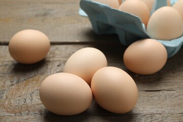 Raw chicken eggs on wooden table, closeup