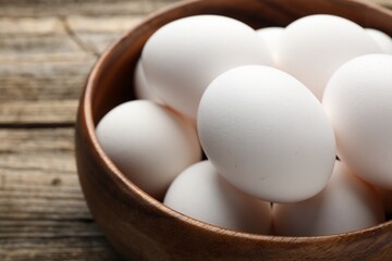Fresh chicken eggs in bowl on wooden table, closeup