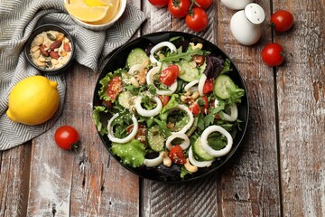 Delicious squid salad and ingredients on wooden table, flat lay
